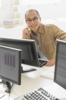 Korean businessman smiling at computer at office desk