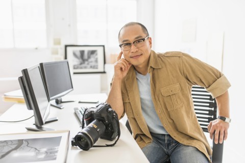 Korean photographer smiling at desk