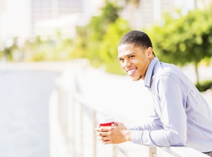 Black businessman leaning on banister at waterfront