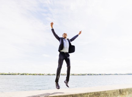 Black businessman jumping for joy outdoors
