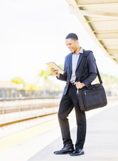 Black businessman using digital tablet on train platform