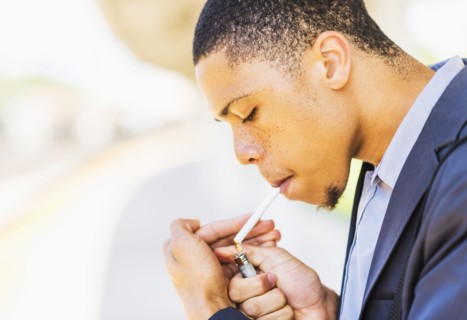 Black businessman lighting cigarette outdoors