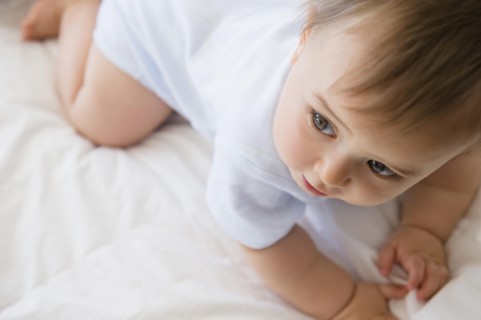 Close up of mixed race baby crawling on bed