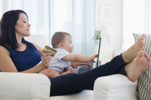 Mixed race mother holding baby and shopping on laptop