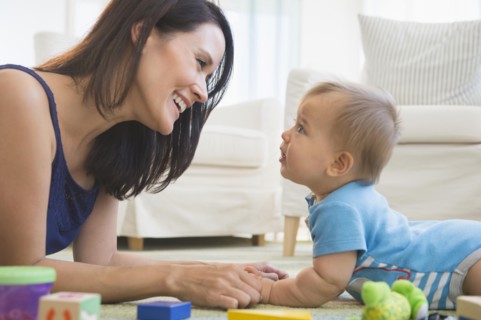 Mixed race mother playing with baby on floor