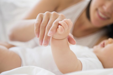 Mixed race mother playing with baby on bed