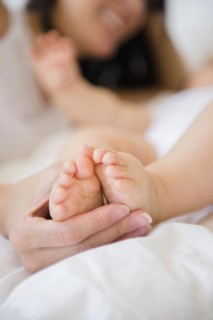 Close up of mixed race mother holding feet of baby