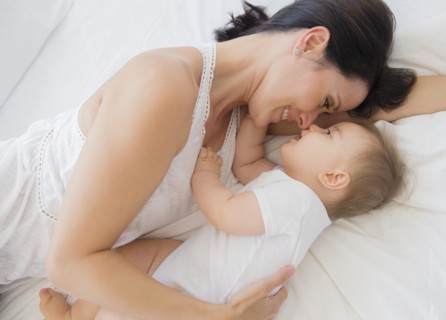 Overhead view of mixed race mother laying with baby on bed