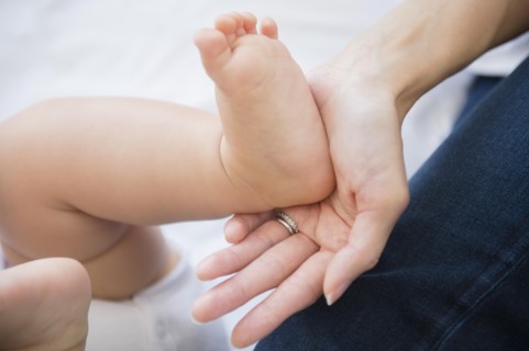 Close up of mixed race mother holding foot of baby