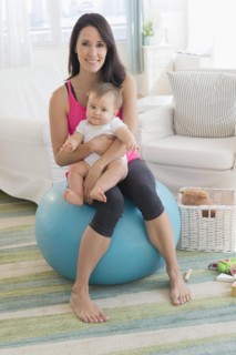 Mixed race mother holding baby on fitness ball