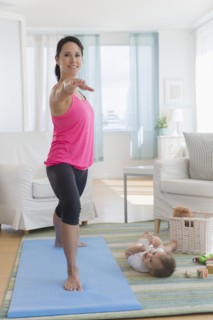 Mixed race mother practicing yoga and watching baby at home