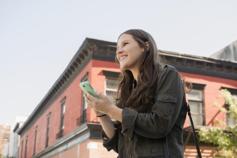 Low angle view of Caucasian woman using cell phone outdoors