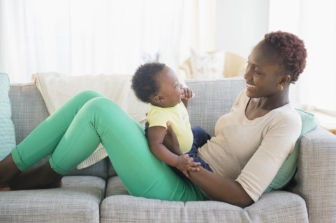 Black mother and son playing on sofa