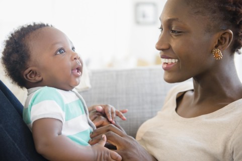 Black mother and son playing on sofa