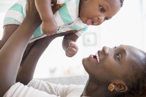 Black mother and son playing on sofa