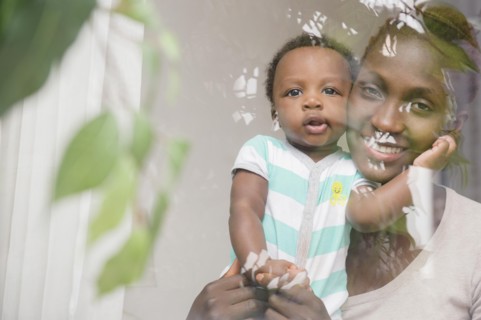 Black mother and son looking out window