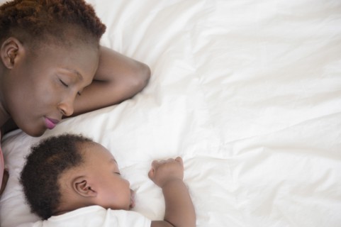 Black mother and son sleeping on bed