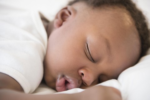 Close up of Black baby boy sleeping on bed