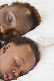 Black mother and son sleeping on bed