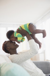 Black mother playing with baby boy on sofa