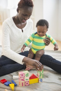Black mother playing with baby boy in living room