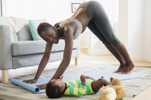 Black mother practicing yoga with baby boy in living room