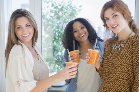Women drinking healthy juice near window