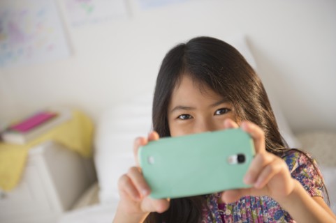 Smiling Vietnamese girl taking cell phone photograph