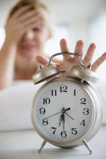 Caucasian woman shutting off alarm clock