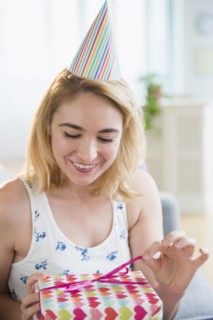 Caucasian woman unwrapping birthday present at party
