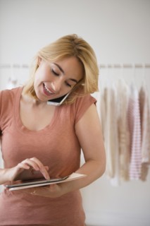 Caucasian woman using digital tablet in clothing store