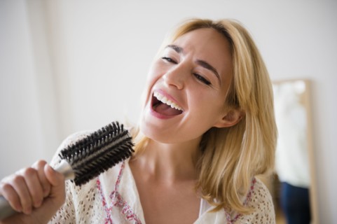 Caucasian woman singing into hairbrush