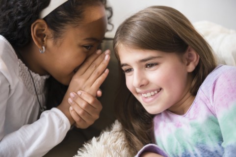 Smiling girls whispering on sofa