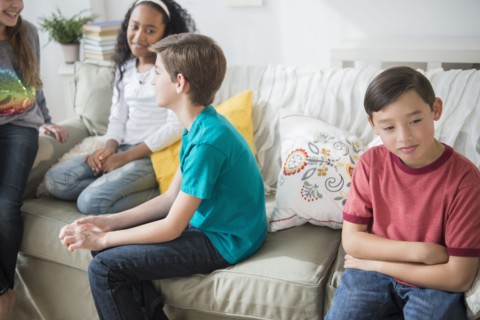 Pouting boy ignoring friends in living room