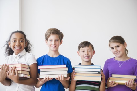 Students holding stacks of books
