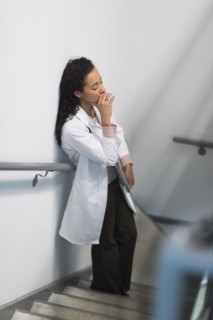 High angle view of stressed mixed race doctor standing on staircase