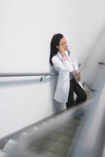High angle view of stressed mixed race doctor standing on staircase