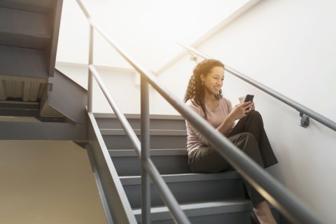 Low angle view of mixed race businesswoman using cell phone on staircase