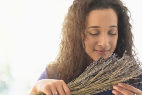 Close up of mixed race woman smelling dried lavender flowers