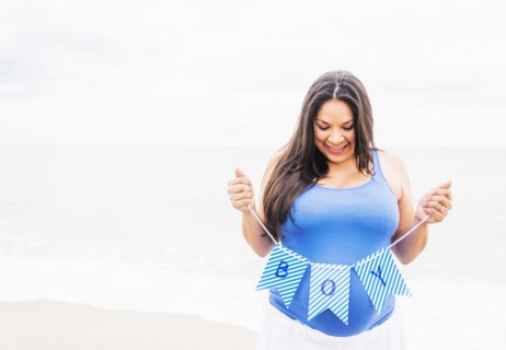 Pregnant mixed race woman holding boy banner on beach