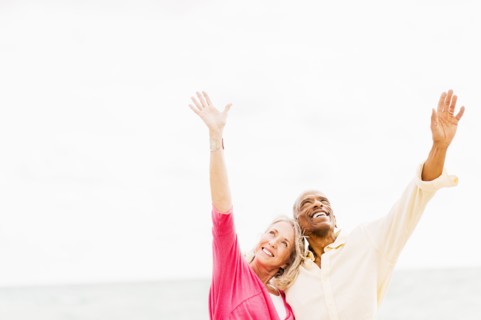 Older couple cheering and hugging on beach