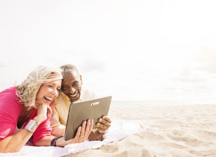 Older couple using digital tablet on beach