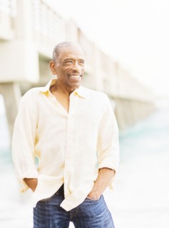 Older mixed race man smiling under boardwalk on beach