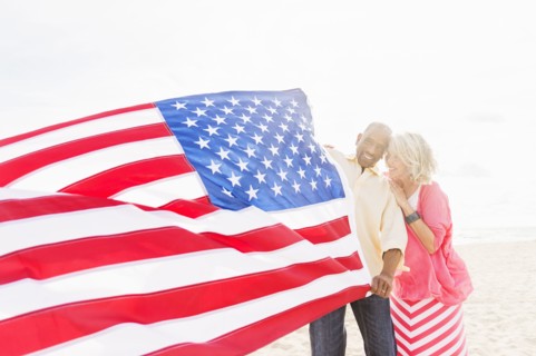 Older couple holding American flag on beach