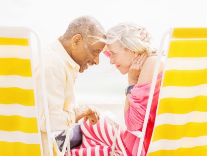 Older couple sitting in lawn chairs on beach