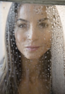 Caucasian woman peering through wet window