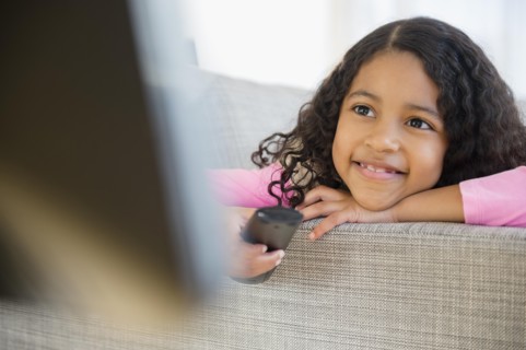 Mixed race girl watching television on sofa