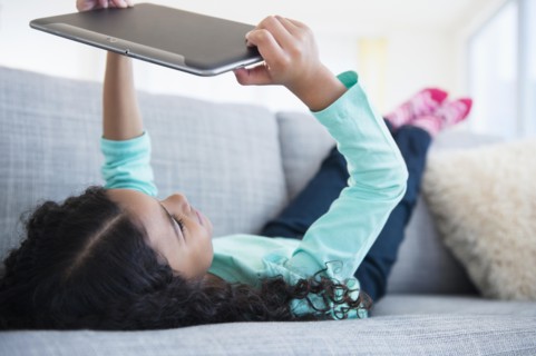 Mixed race girl using digital tablet on sofa