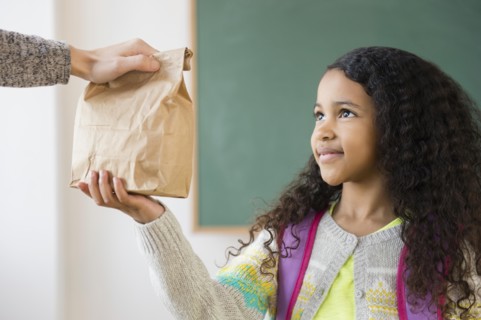 Student taking brown bag lunch in classroom