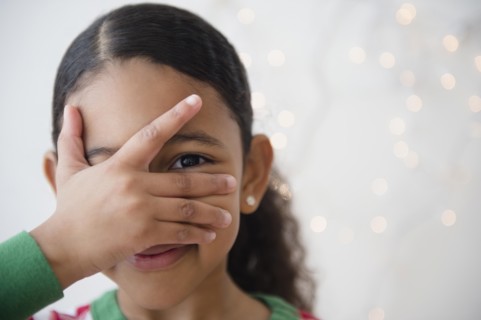 Close up of mixed race girl peeking between fingers